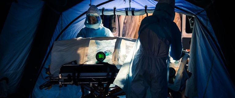 Infectious disease researchers in a tent wearing protective gear