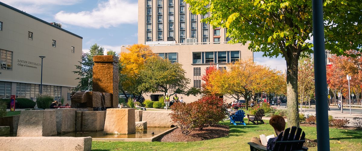 A student sits on the BU School of Communications lawn