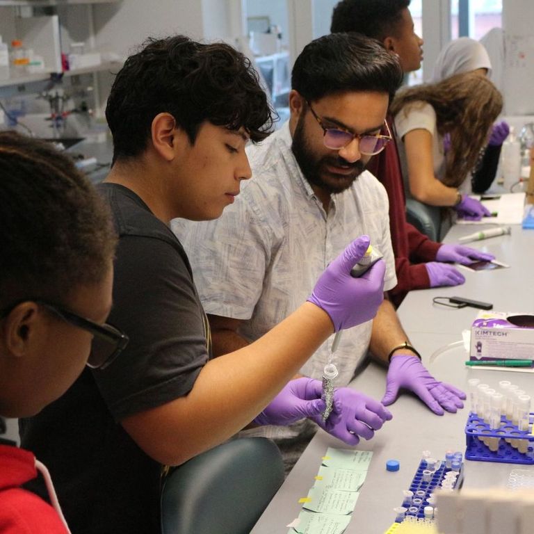 People gathered at a table in a lab looking at samples