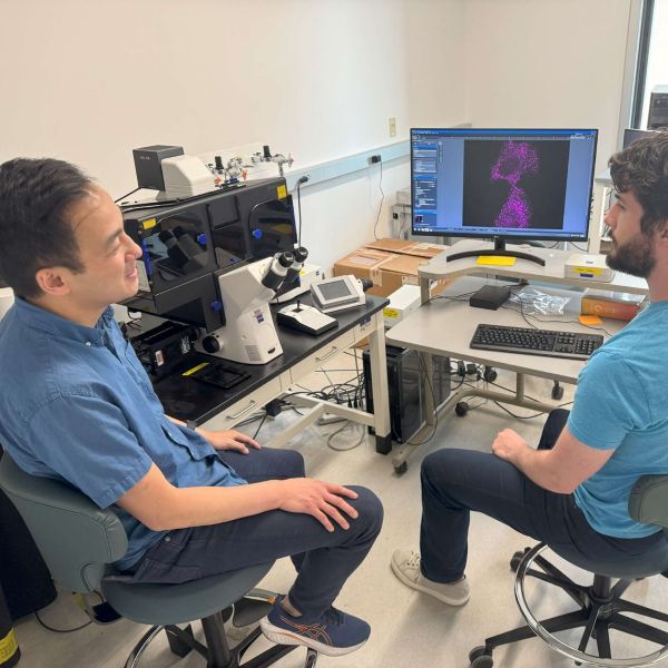 two people seated in front of a computer monitor