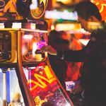 A man is playing an electronic casino game in a neon lit casino.