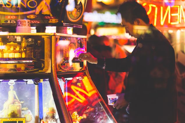 A man is playing an electronic casino game in a neon lit casino.