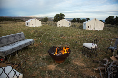 A fire pit surrounded by outdoor coaches and glamping tents