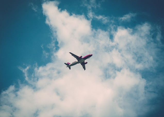 Shot from below of an airplane flying with clouds in the sky