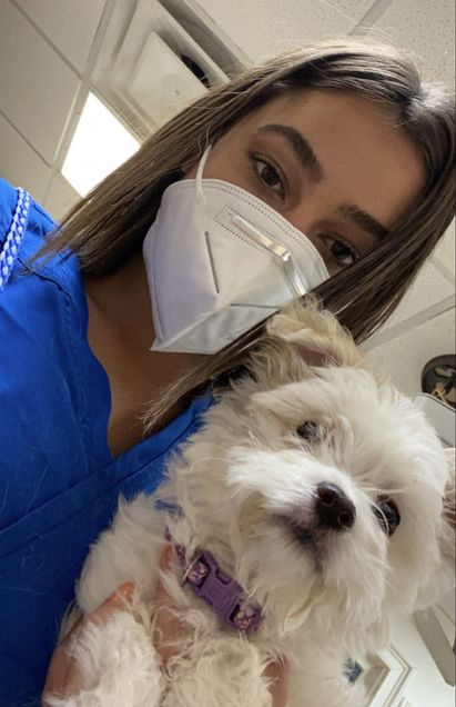 Marisa holding a dog at a veterinary hospital.