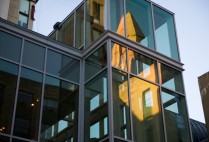 CAS tower reflects in the glass of the new The Sumner M. Redstone building in the evening light