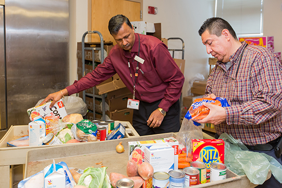 Latchman Hiralall, manager of Boston Medical Center’s Preventive Food Pantry (left), and food pantry assistant Juan Carlos Turcios prepare a cart of food for a patient. Photos by Dana J. Quigley