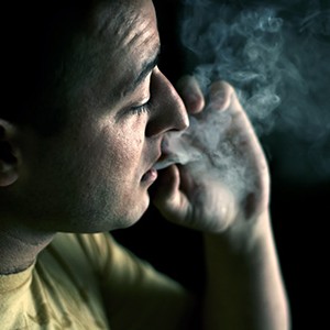 young man smoking weed in a dark room