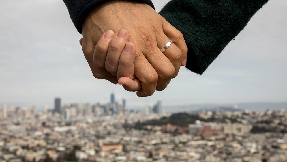 a married couple in san francisco california hold hands with the city in the background