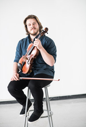 Contemporary music composer Nicholas Quigley poses with violin