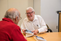 Geoffrey M. Cooper (right), a College of Arts & Sciences professor of biology, signs copies of his novel The Prize