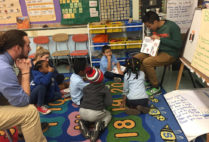 BUILD tutors and students gather on the carpet to listen to a book read aloud.