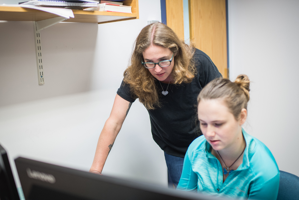 Emily Ryan and a graduate students look intently at a computer screen 