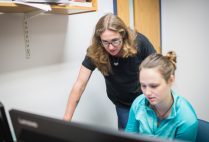 Emily Ryan and a graduate students look intently at a computer screen