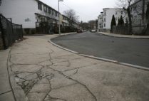 The cracked sidewalk outside of the entrance to the playground behind the Trotter School in the Dorchester neighborhood of Boston