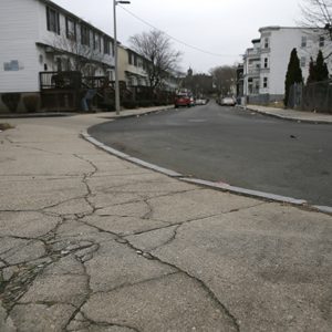 The cracked sidewalk outside of the entrance to the playground behind the Trotter School in the Dorchester neighborhood of Boston