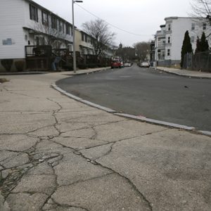 The cracked sidewalk outside of the entrance to the playground behind the Trotter School in the Dorchester neighborhood of Boston