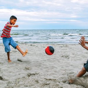kids playing soccer on the beach