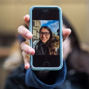 Lexi Herosian holding a phone with a photo of herself on it