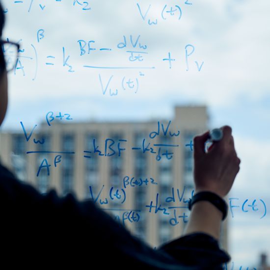 A researcher writes equations on the window of BU’s Kilachand Center for Integrated Life Sciences & Engineering