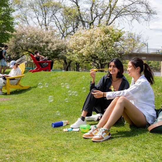 Mira Khanna (CAS’24), left, and Jasmine Wei (CAS’24) lounge and blow bubbles together on the BU Beach