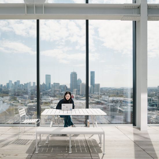 A student studies at the Duan Family Center for Computing & Data Sciences, with a view of the Boston skyline and Charles River behind them