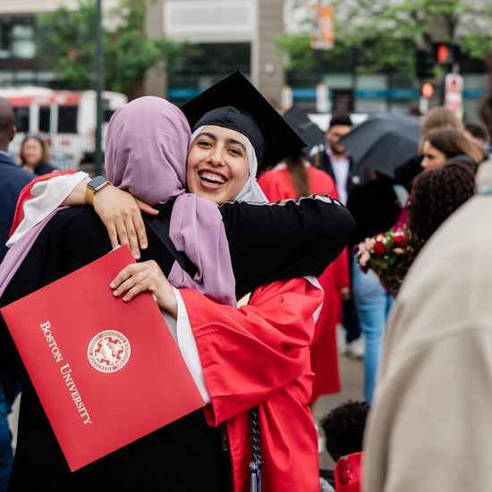 Graduates hug on Commonwealth Avenue during Commencement festivities