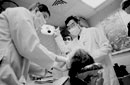 At the Oral AIDS Clinic, Laisheng Lee Chou (right) guides senior dental students in the examination and treatment of HIV-positive patients. Photo by Kent Dayton