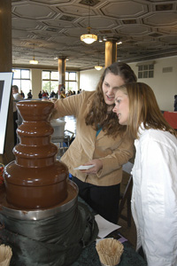 Leanne Palmer, a BU culinary arts student, and Devon Harrison experiment with the chocolate fountain at the New England Chocolate Festival. Photo by Albert LEtoile
