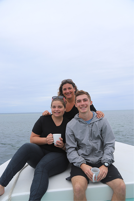 Hayley Goss, professor Randi Rotjan, and Jacob Jaskiel pose for a photo during a morning boat ride near Turneffe Atoll, Belize.