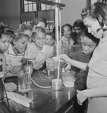 Students crowded around a teacher performing a science experiment