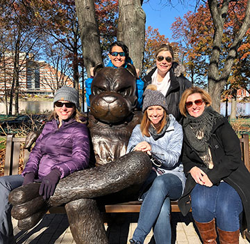 A group of alum from the class of '96 sitting with the Rhett statue on campus
