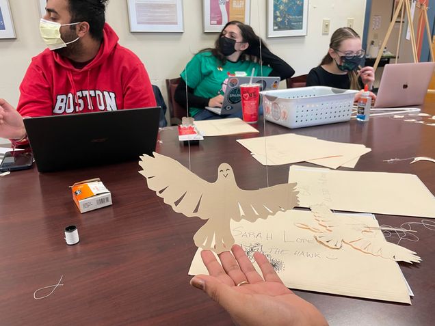 A student holds a paper hawk puppet.