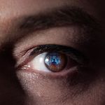 Closeup of eye with a reflection of a person working on a computer