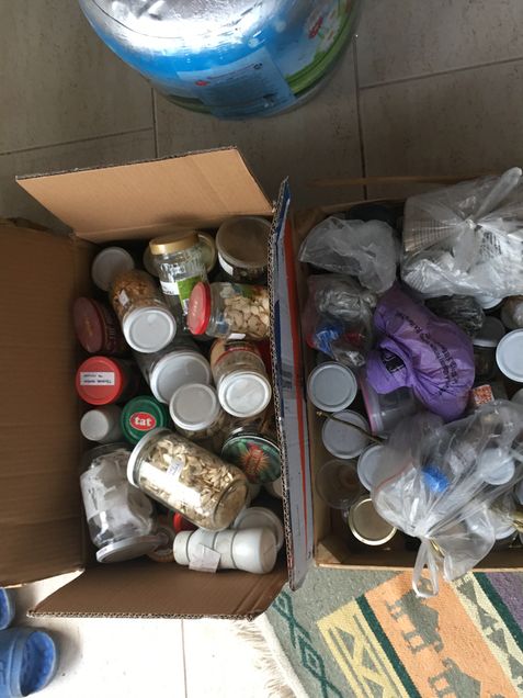 A farmer's seed collection is contained in plastic bottles within two cardboard boxes.