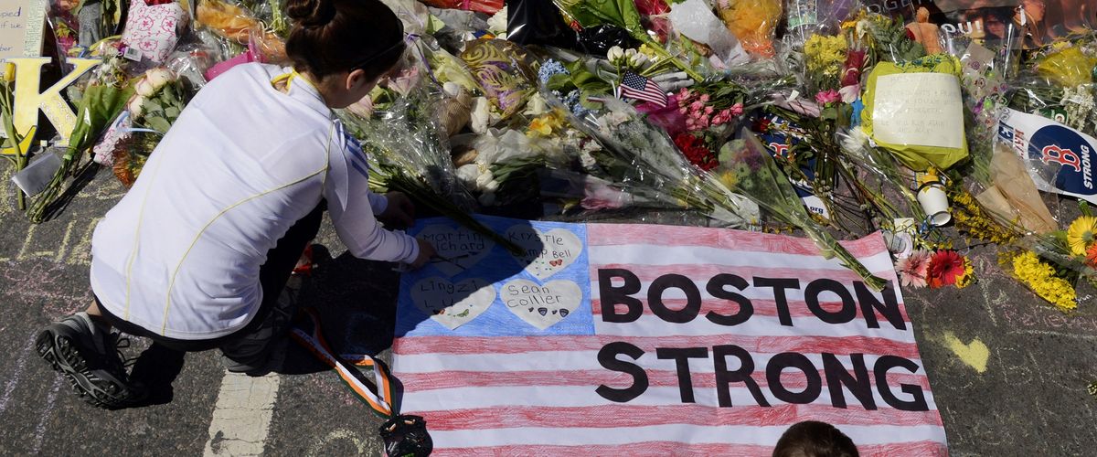 Photo of a girl and boy kneeling at a Boston Strong memorial