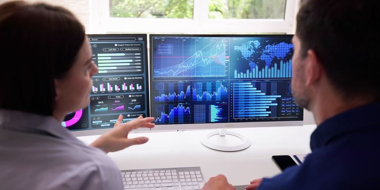 Photo of two people pointing at a computer screen of data visualization from behind