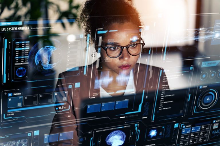 An image of a female data scientist working at her computer with an overlay of digital images on her screen.