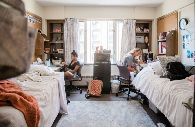 two female students studying at thier desks in a dorm room