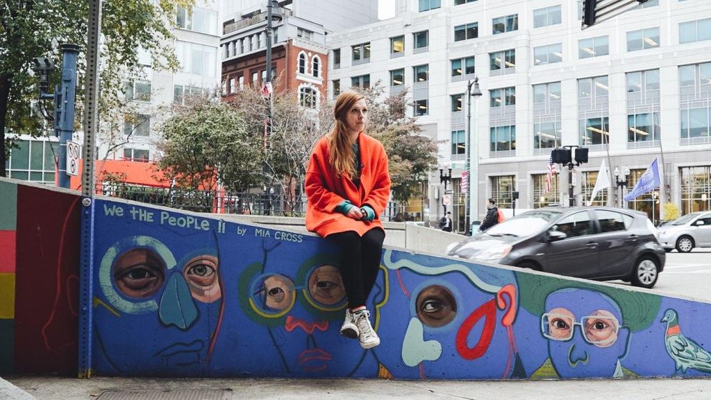 Mia Cross sits at her mural, We the People II