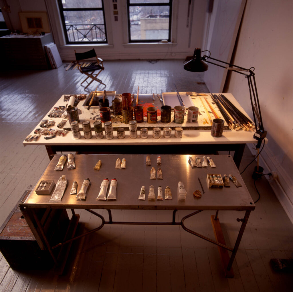 Brice Marden's New York studio showing two tables with paints and paintbrushes.