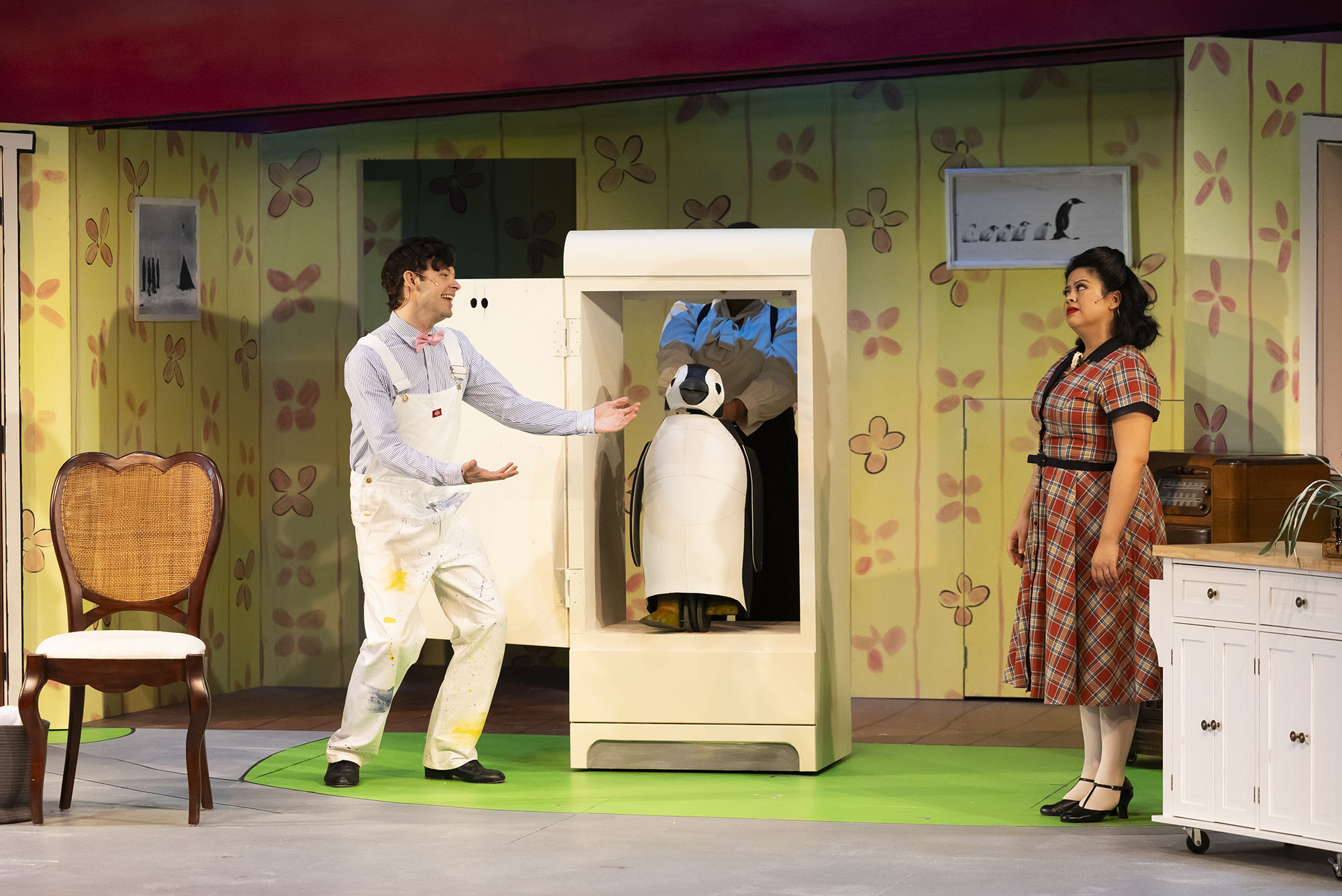 Michael Jennings Mahoney (far left standing with a smile on his face) and Kristian Espiritu (far right standing with a stern look on her face) star as Mr. and Mrs. Popper in Wheelock Family Theatre’s production of Mr. Popper’s Penguins, based on the novel by Richard and Florence Atwater.