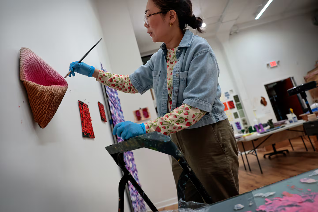 Artist Lucy Kim works on a sculptural painting at her studio in Somerville, MA