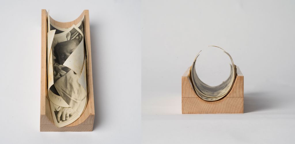 Two views of a curved wooden block holding a rolled and partially unrolled vintage black-and-white photograph. The photo appears aged with some curling and yellowing, and shows a close-up of a person resting, wearing a ring, with the name "Betty" handwritten on it. The left image is a top-down perspective, revealing more of the photograph's content, while the right image shows a front view emphasizing the curved shape of the wooden holder and the rolled photo inside. The background is plain white.
