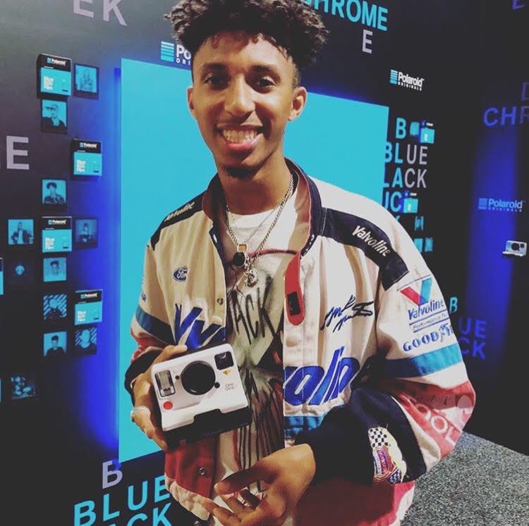 Bruce Dennis holding a Polaroid camera at Complex Con