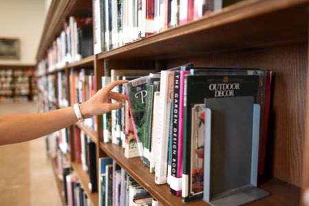 Person pulling a book from a shelf in a library