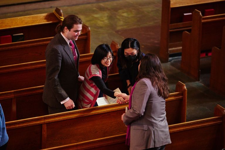 College aged young adults greet eachother in the sanctuary
