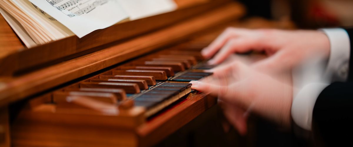 Close up of fingers playing the organ with sheet music in front of them