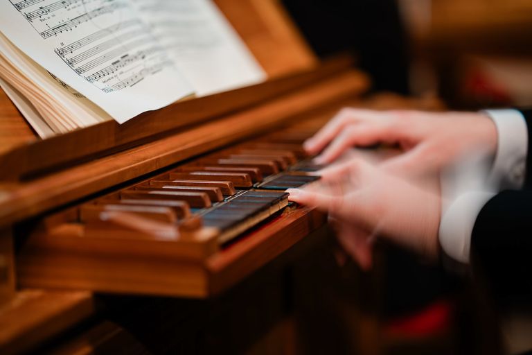 Close up of fingers playing the organ with sheet music in front of them