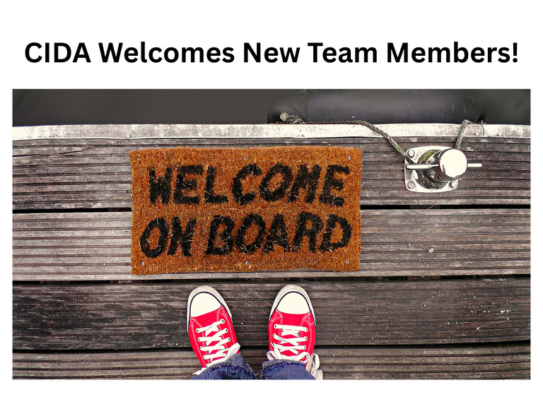 A welcome mat with the words welcome on board inscribed on the mad lays flat on a dock above the image of a person's red shoes